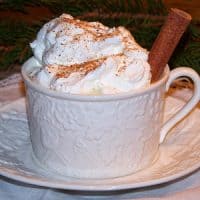 Cup full of eggnog with whipped cream on top.
