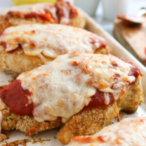 Pan of easy baked chicken parmesan with melted cheese on top.