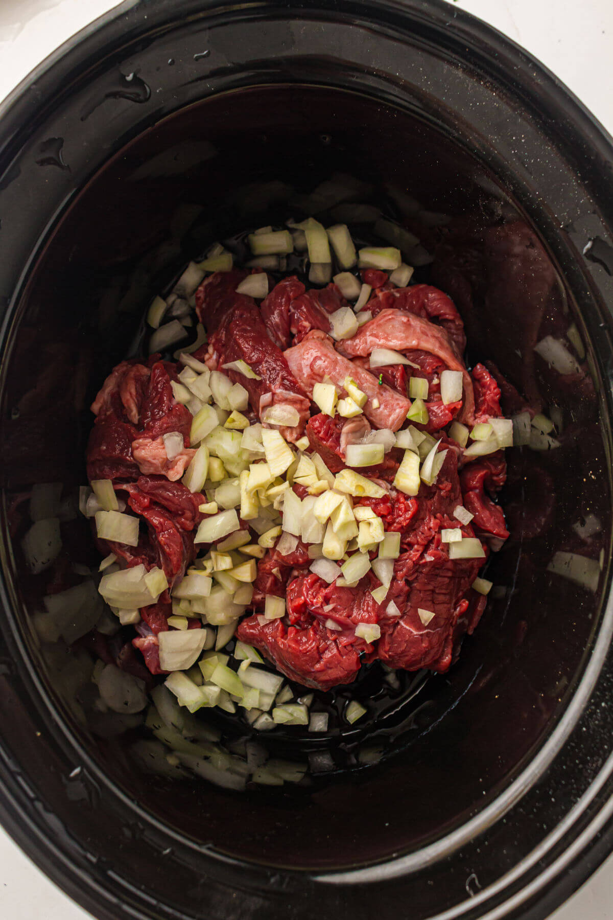 Adding beef and vegetables to slow cooker beef and broccoli.