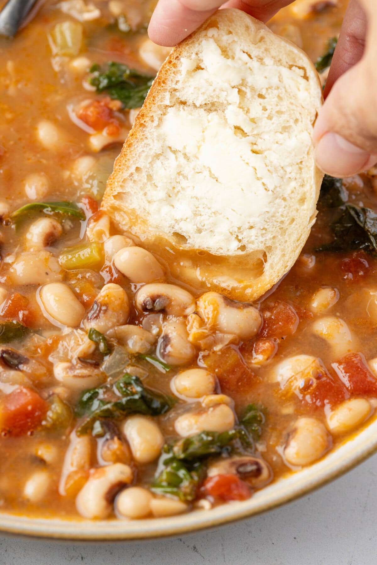 Black eyed pea soup in a bowl with buttered bread.