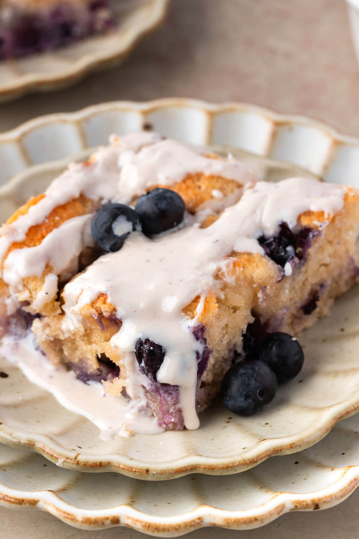 Sourdough butter swim biscuits with blueberries and frosting on a plate.