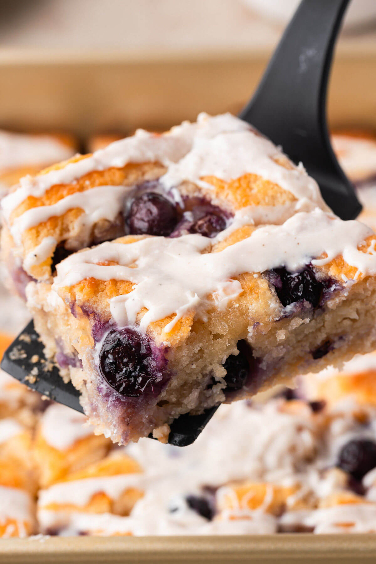A square of blueberry sourdough butter swim biscuits being served with a spatula.