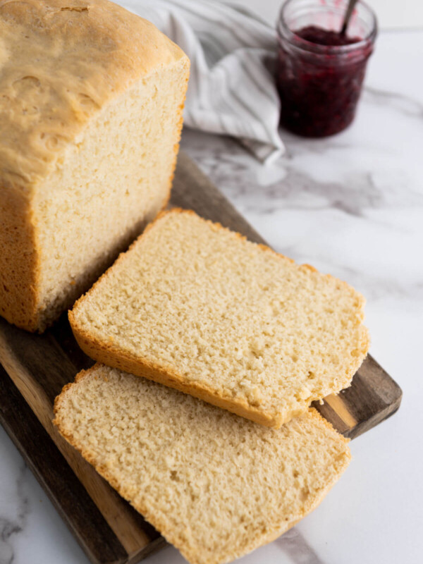 Loaf of simple bread machine white bread on a wooden cutting board.