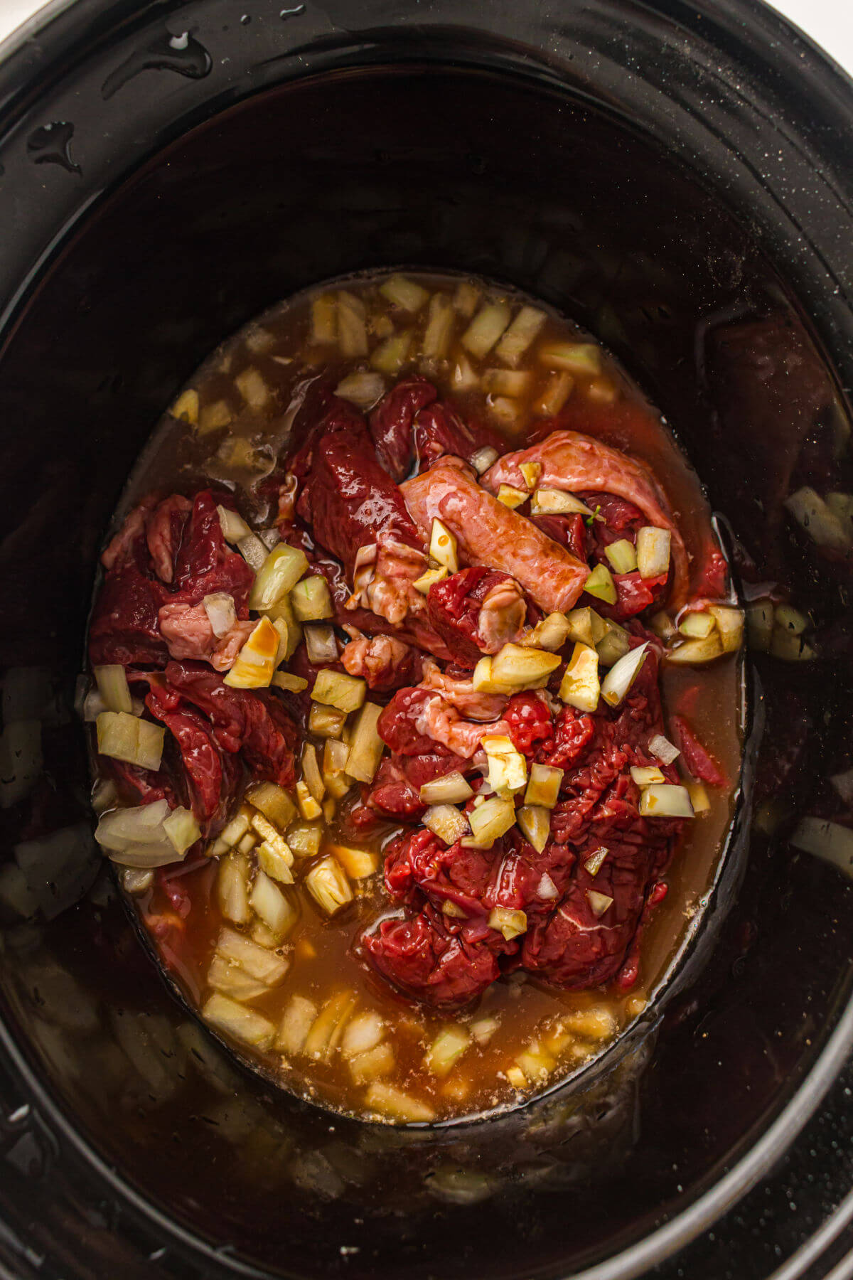 Adding broth to slow cooker beef and broccoli.