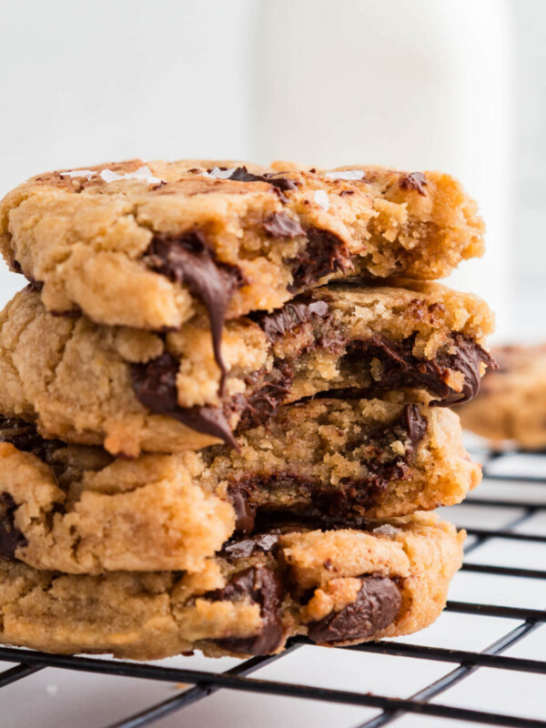 A pile of brown butter sourdough chocolate chip cookies on a wire cooling rack.