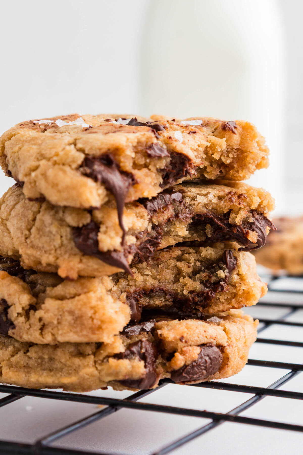 A pile of brown butter sourdough chocolate chip cookies on a wire cooling rack.