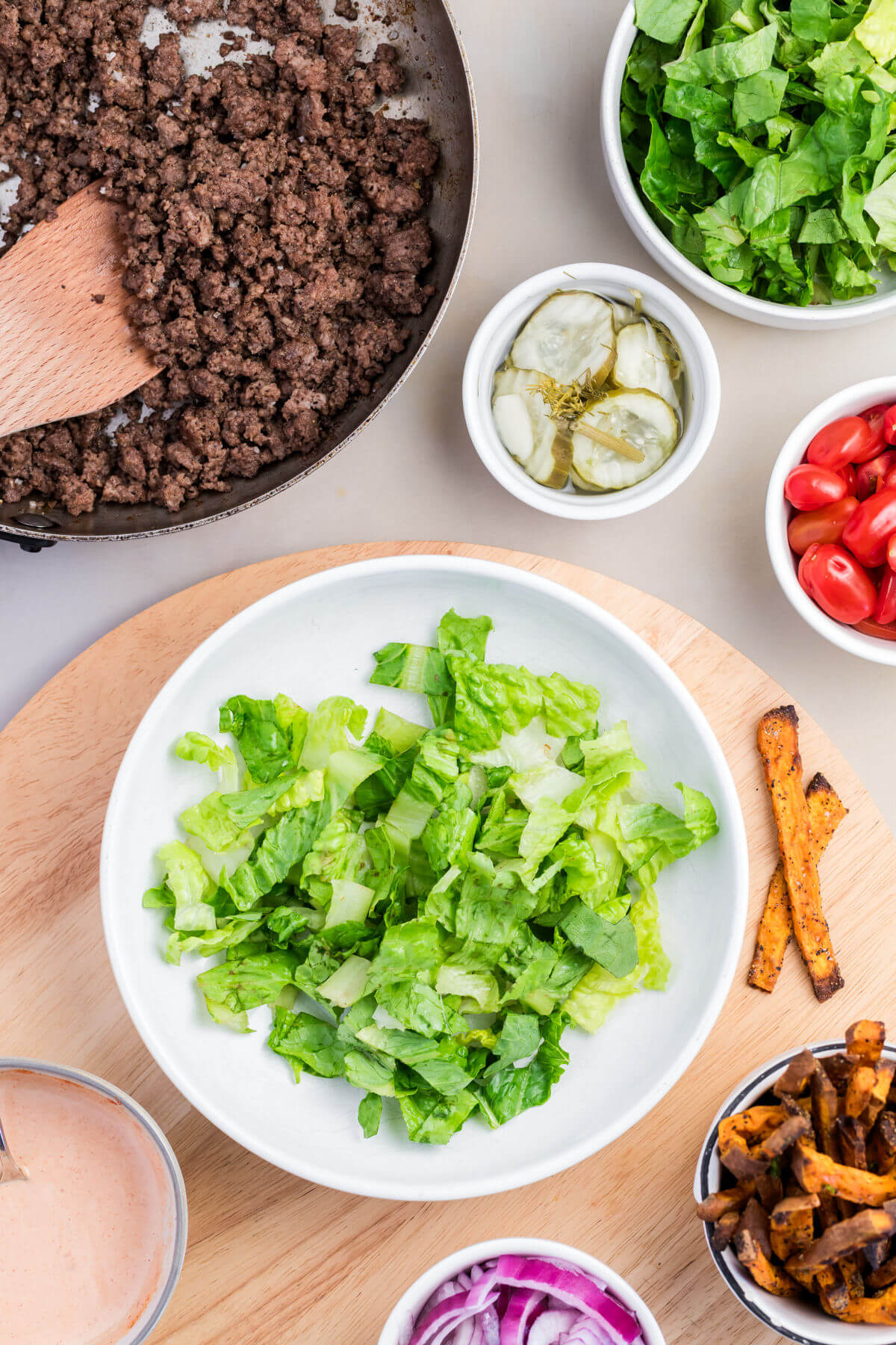 Photo showing adding lettuce to the burger bowls.