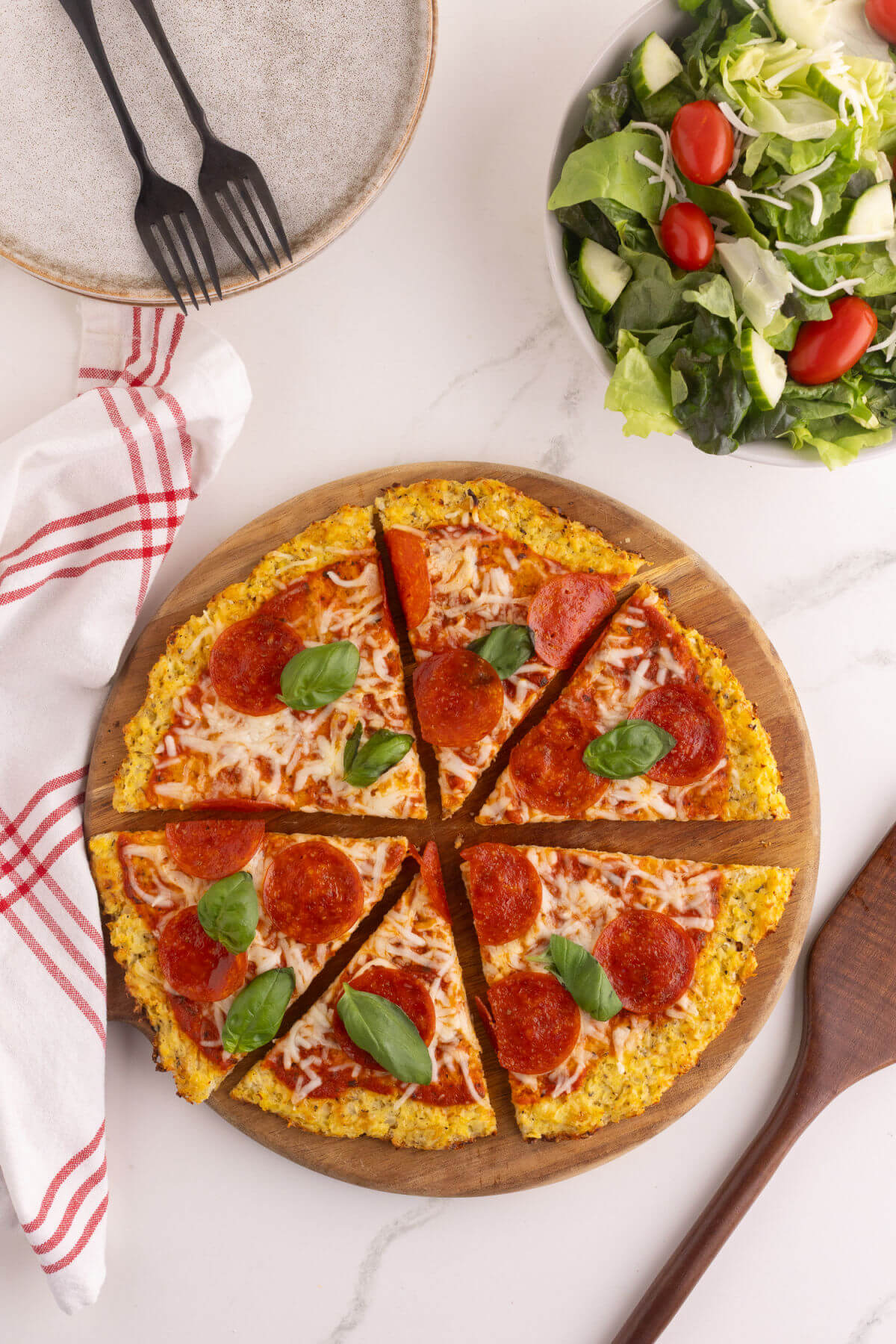 Cauliflower pizza crust after baking with a salad next to it.