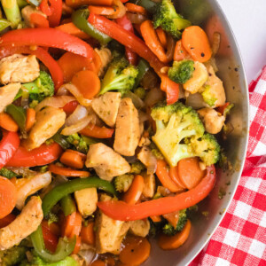 Simple chicken stir fry with vegetables in a stainless steel skillet.