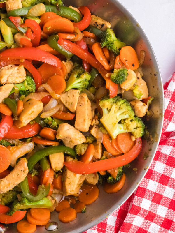 Simple chicken stir fry with vegetables in a stainless steel skillet.