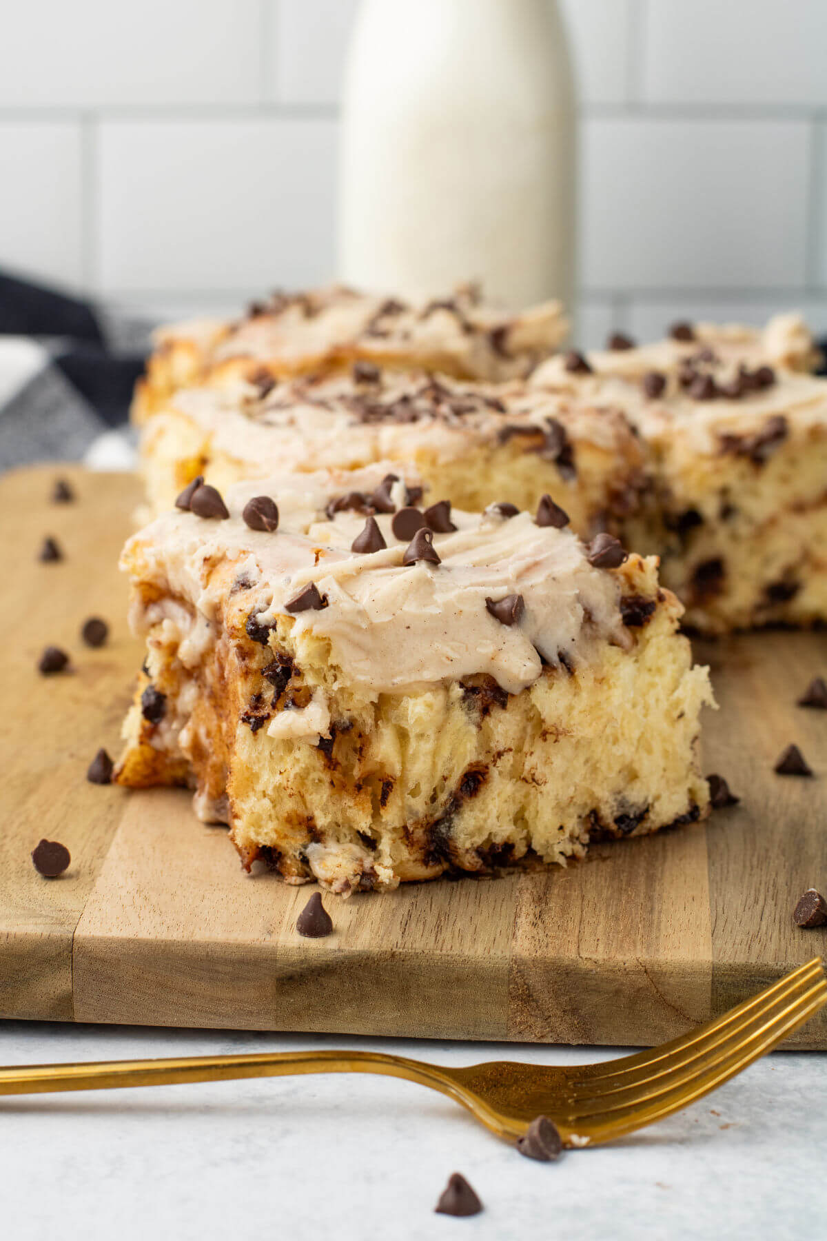 Several baked chocolate chip cinnamon rolls on a wooden board.