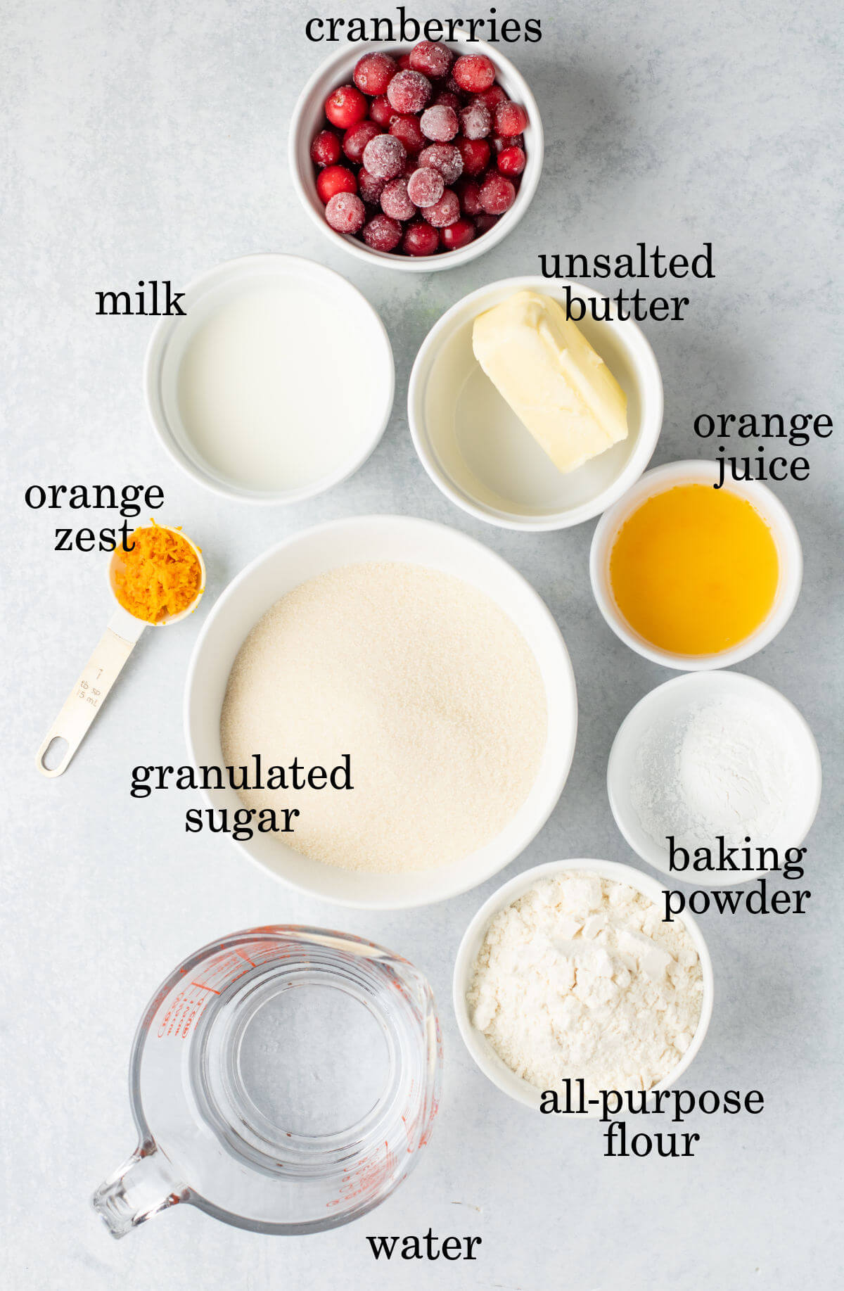 Cranberry orange cobbler ingredients in small bowls with text overlay labeling each ingredient.