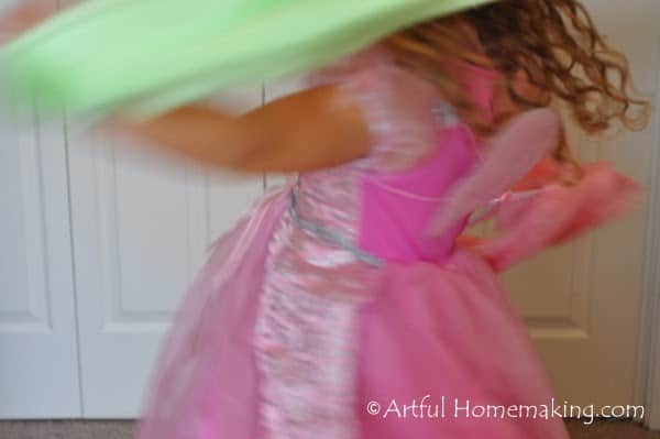 a girl in a pink dress playing with play silks