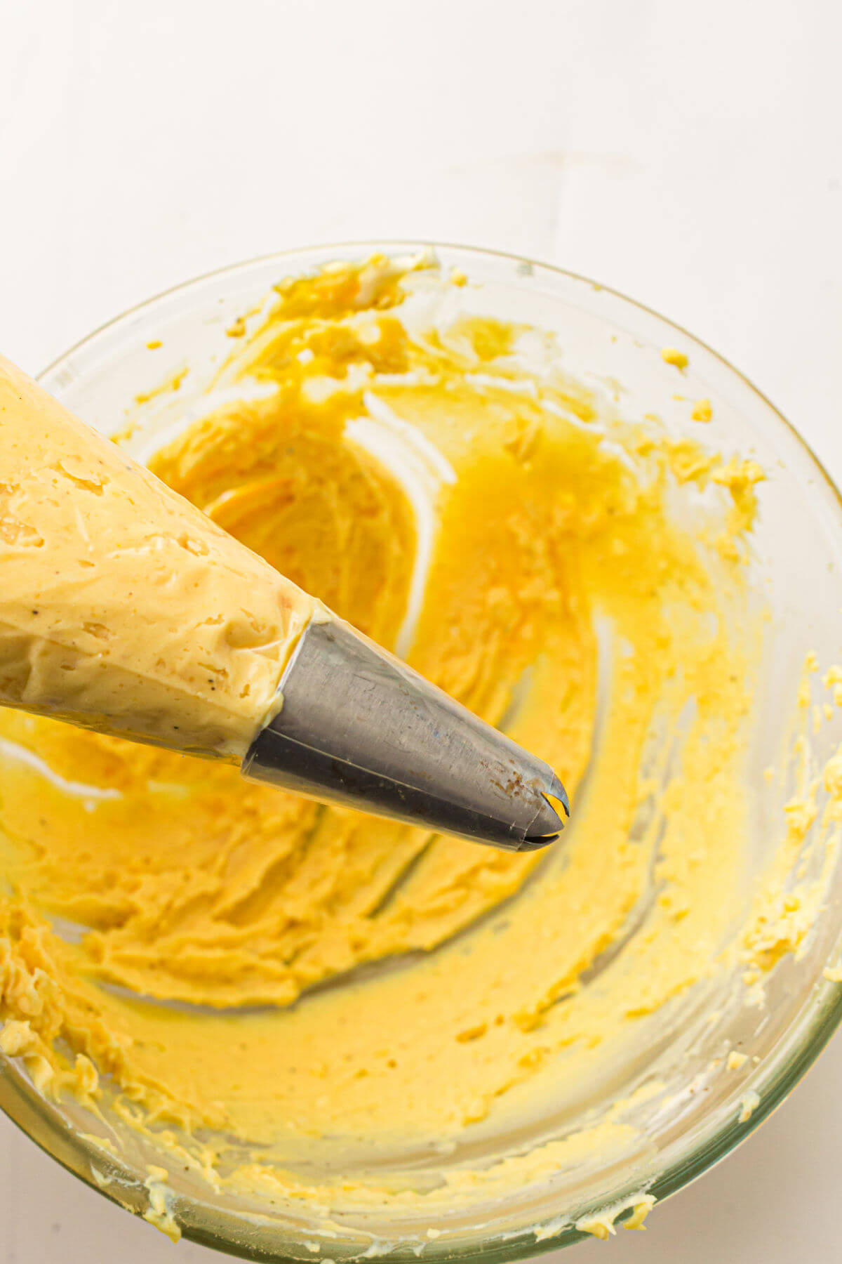 Deviled eggs filling being put into a piping bag.
