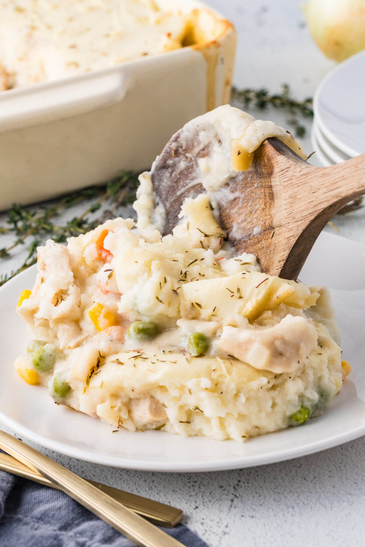A wooden spoon serving chicken shepherd's pie on a plate.