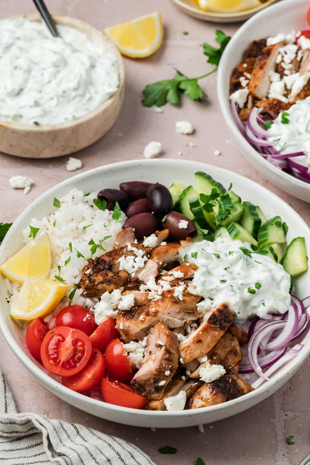 Adding tzatziki sauce to Greek chicken bowls.