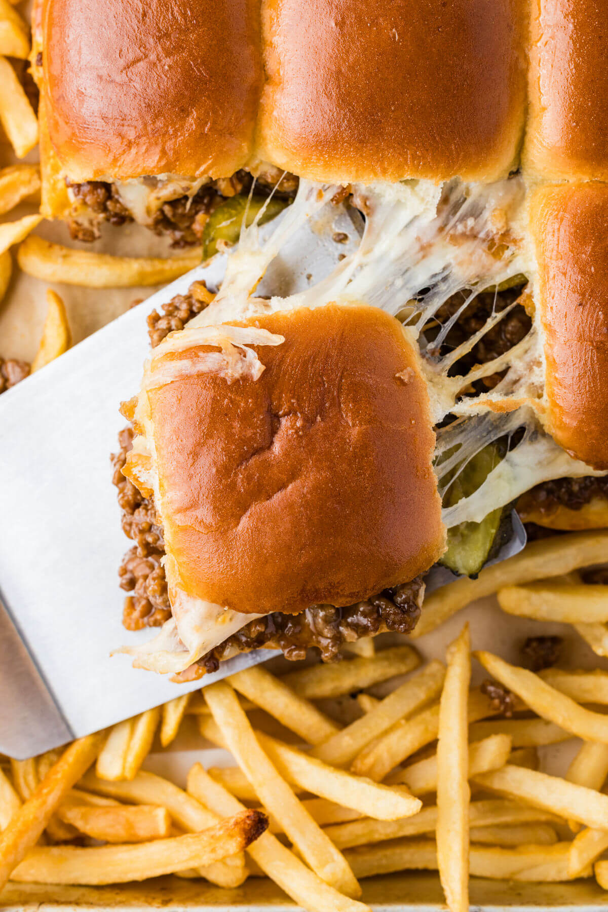 Sloppy joe sliders being served on a tray with french fries.