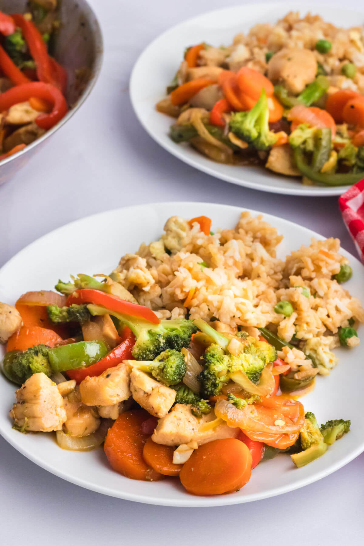 Two plates with simple chicken stir fry on plates.