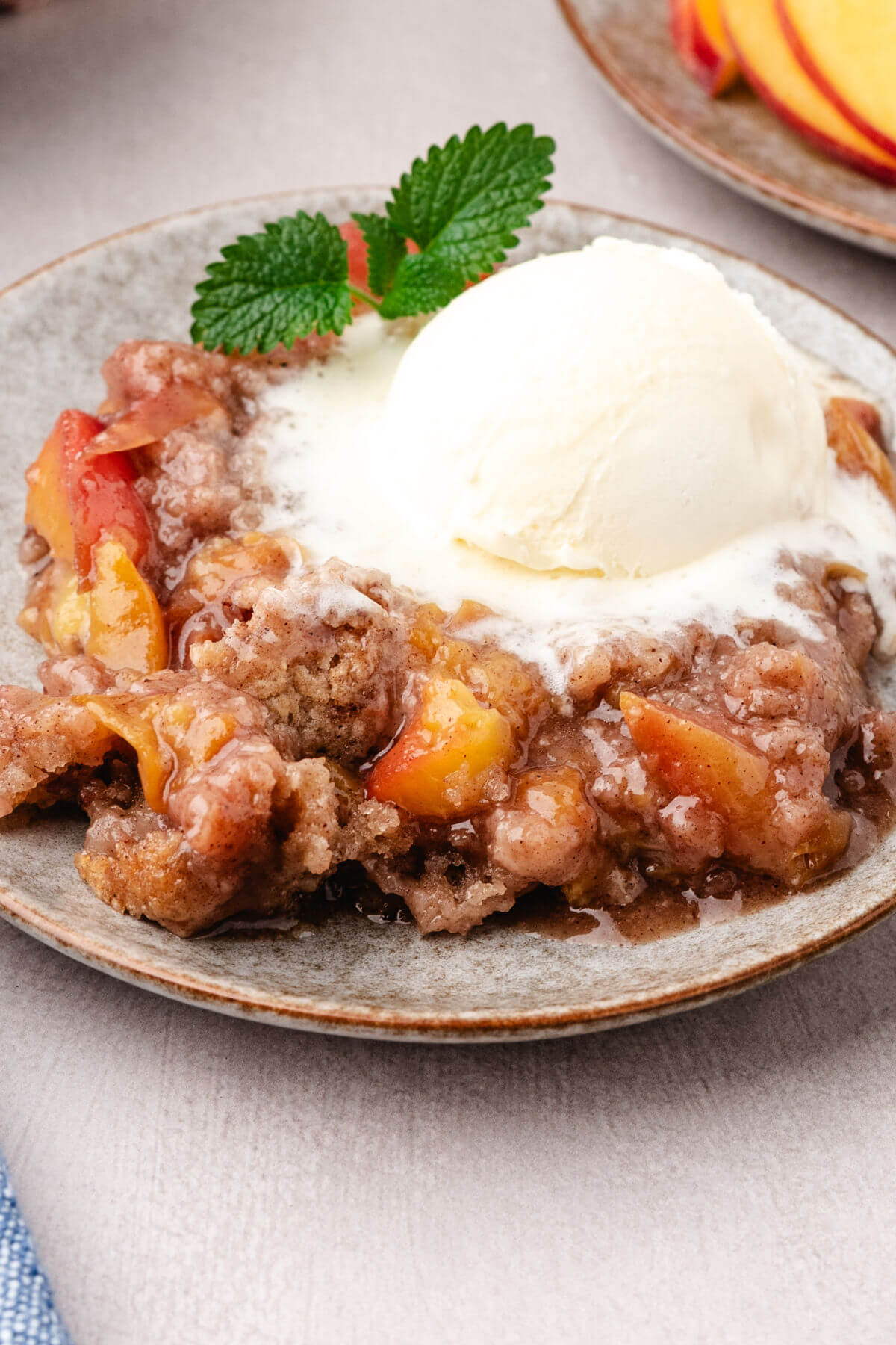 A plate of skillet peach cobbler with vanilla ice cream on top.