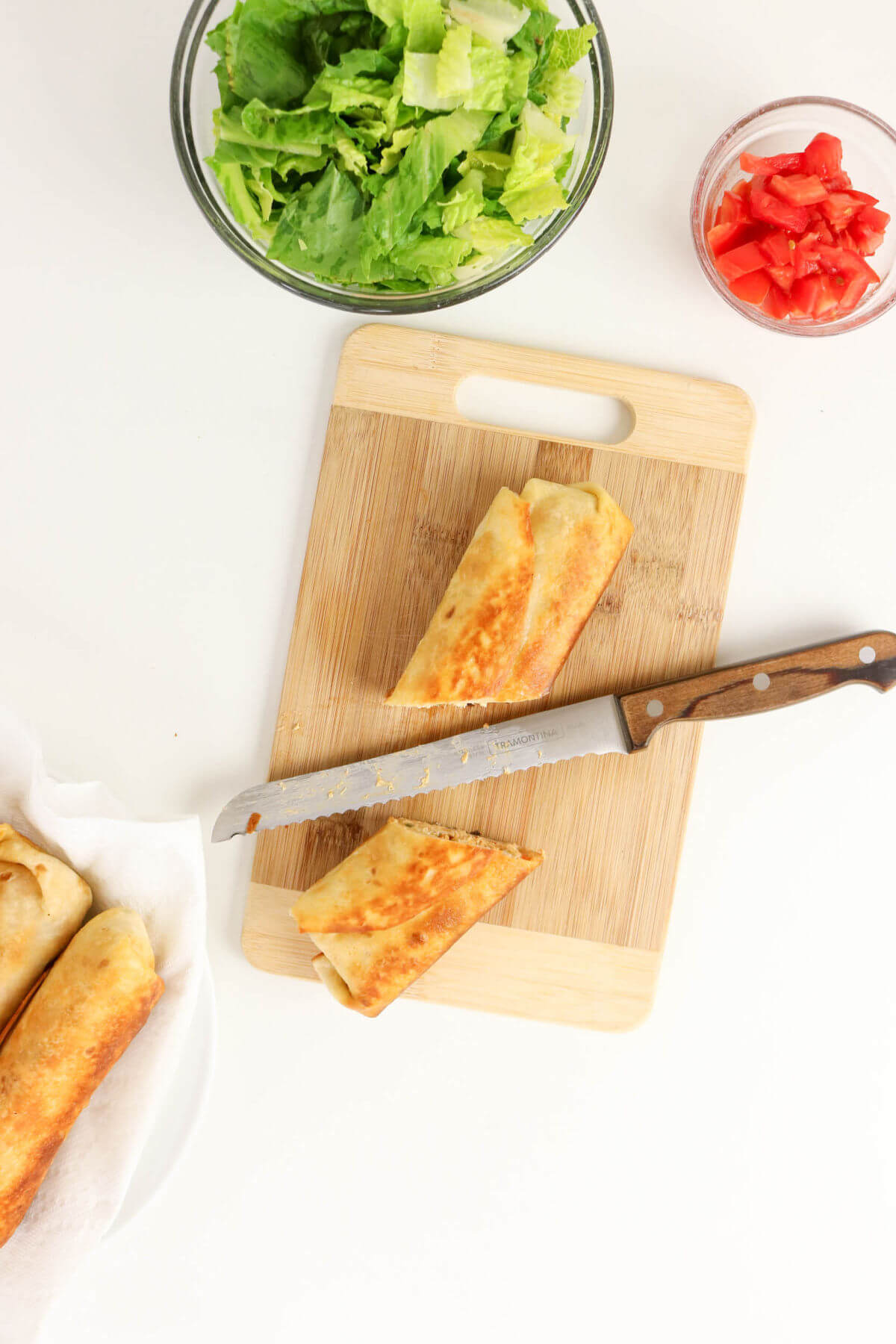 Slicing a firecracker chicken wrap on a cutting board.