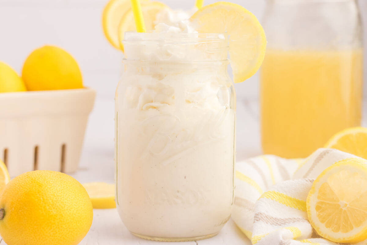 Frosted lemonade in a jar with lemon wedges on the side.
