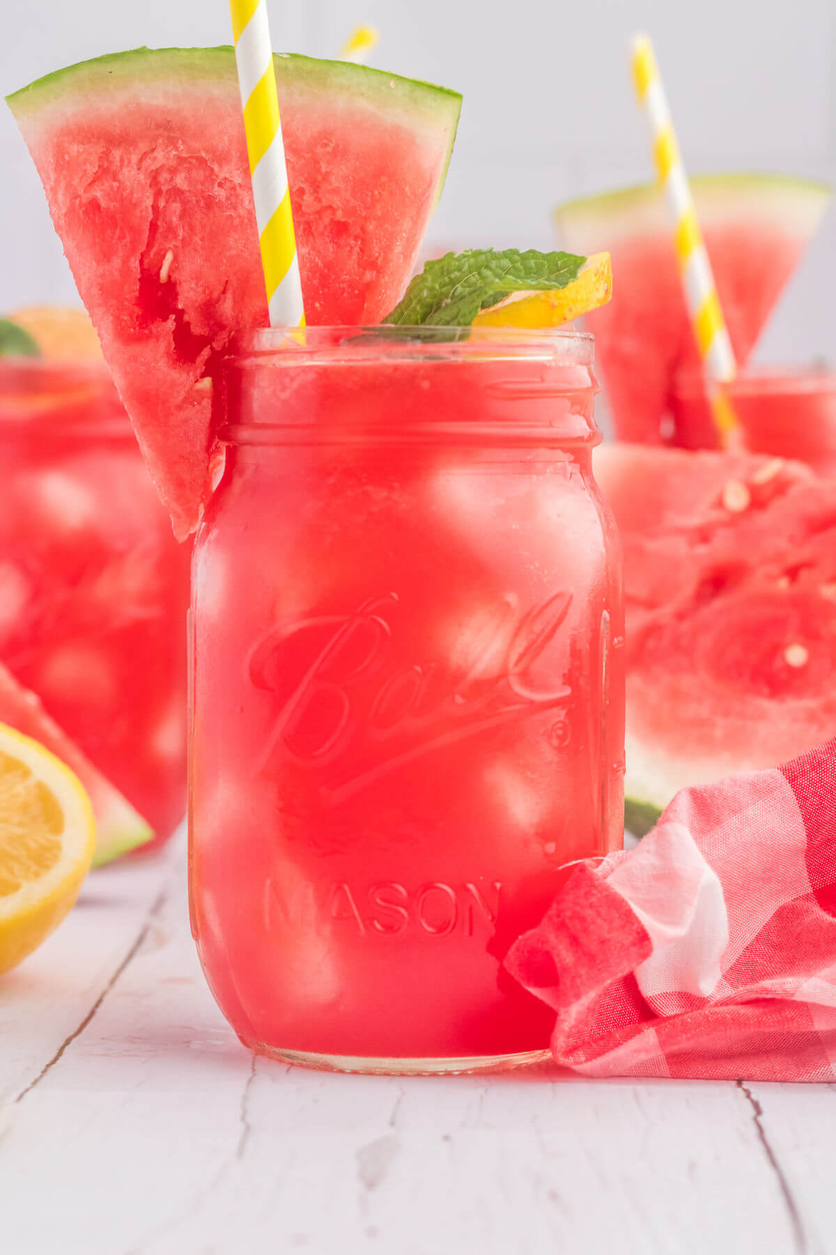 Watermelon lemonade in mason jars with a wedge of watermelon and a mint leaf on the side.