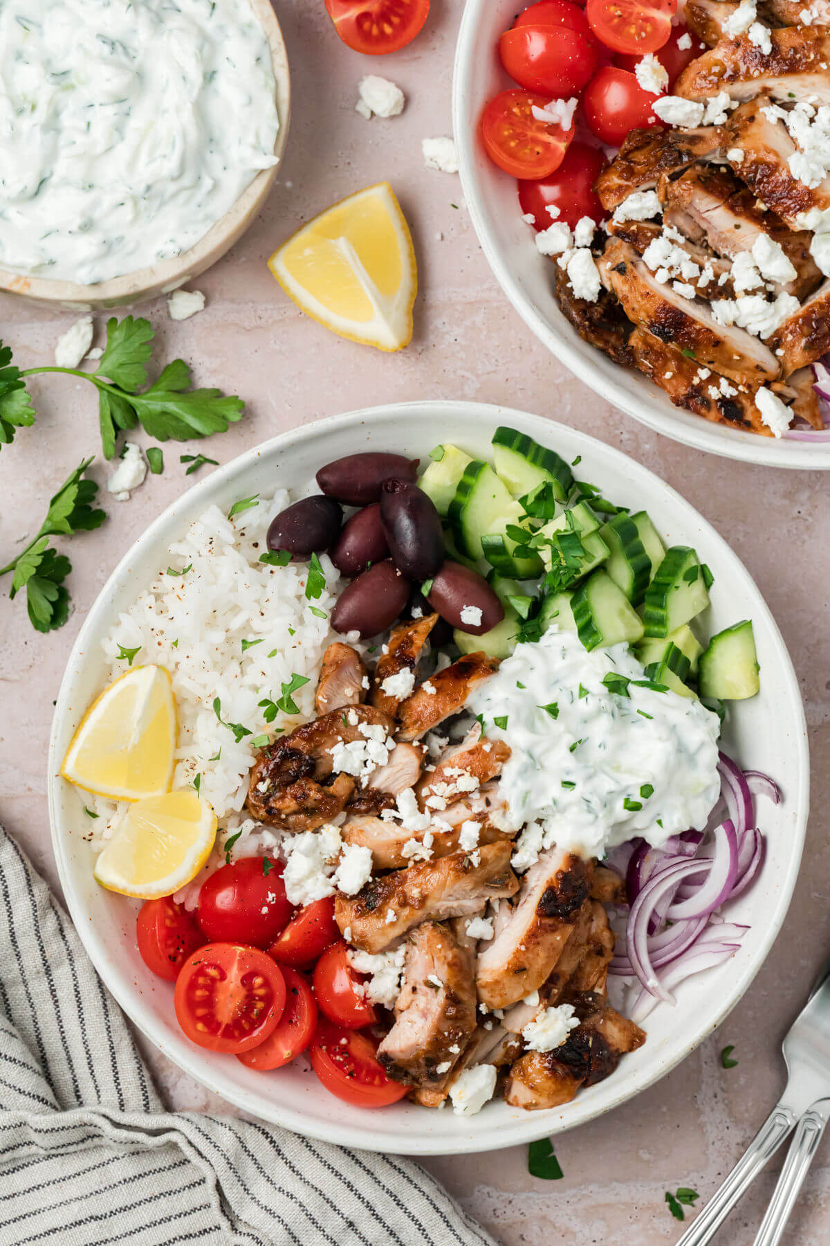 Greek chicken bowls with tzatziki sauce in serving bowls.