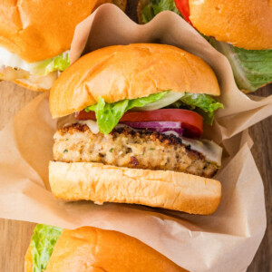 Chicken burgers on a wooden cutting board.