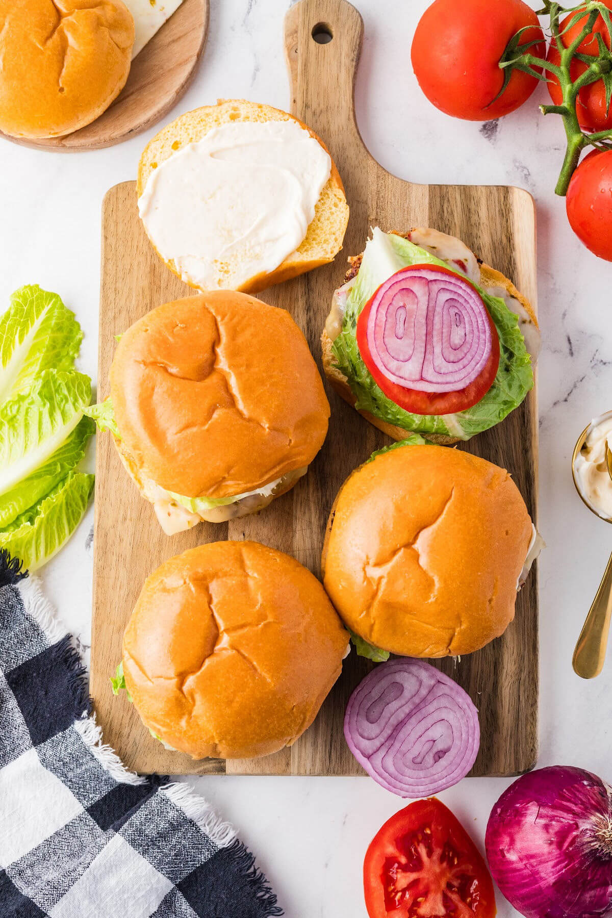 Assembled ground chicken burgers on a cutting board.