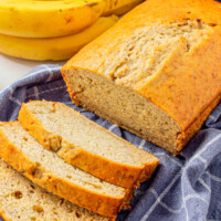 A loaf of quick and easy banana bread cooling on a tea towel.