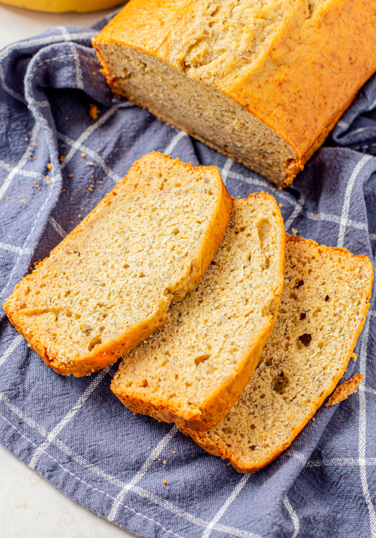 Loaf of quick and easy banana bread on a clean towel with three slices cut.