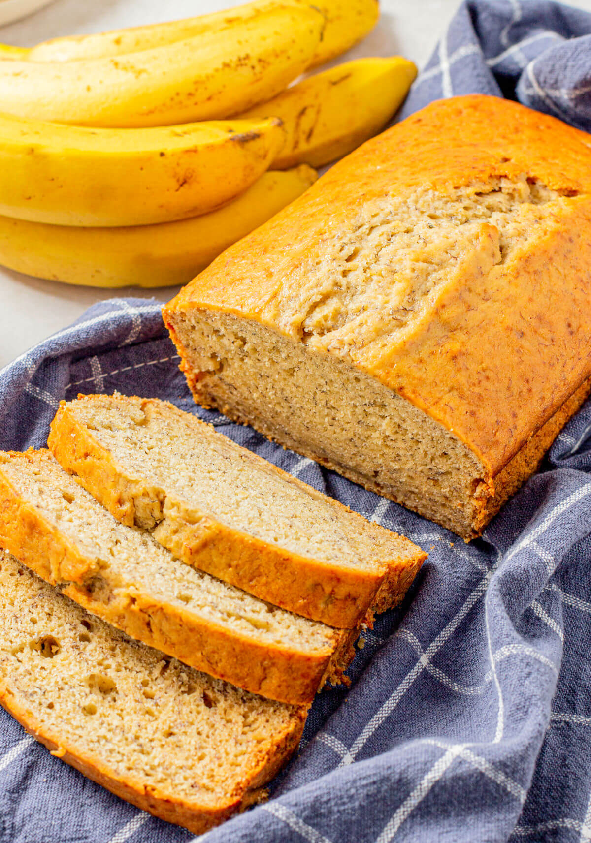 A loaf of quick and easy banana bread cooling on a tea towel.