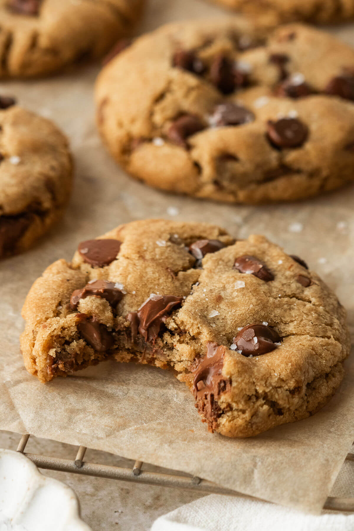 Brown butter chocolate chip cookie on a wire rack with a bite out of it.