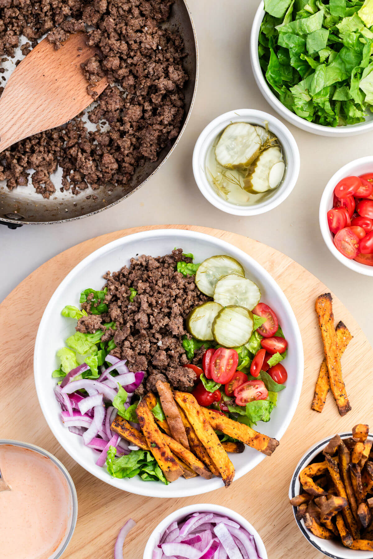 Bowl with ground beef, lettuce, onion, tomatoes, and sweet potato fries for burger bowls recipe.