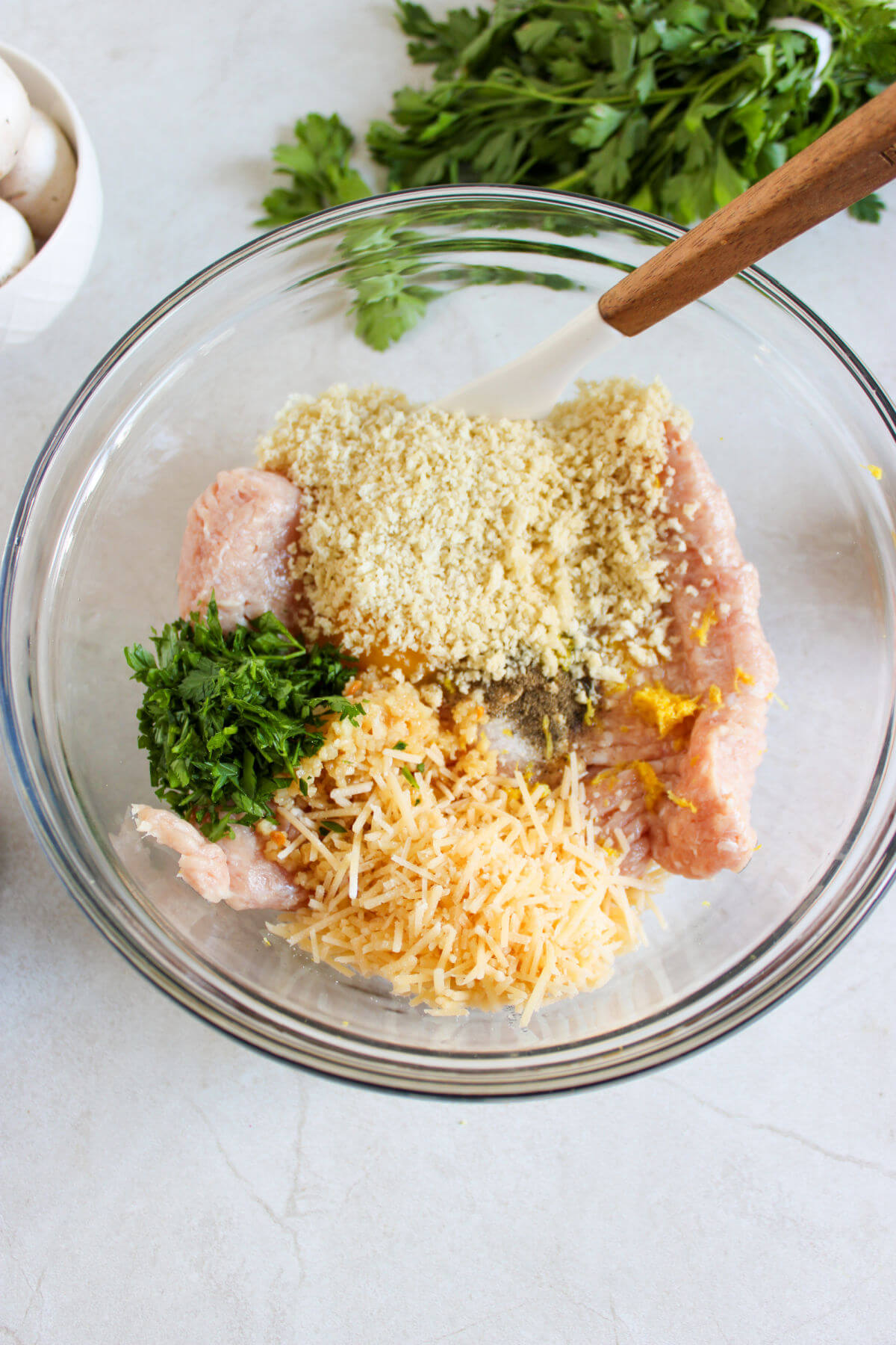 Mixing ingredients for chicken meatballs in a glass mixing bowl.