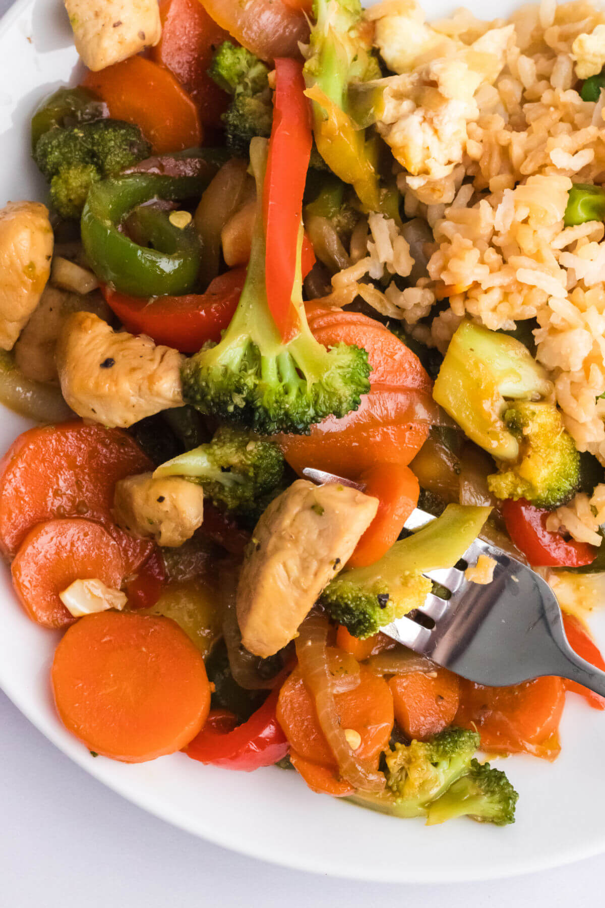 Simple chicken stir fry with vegetables on a plate with rice.