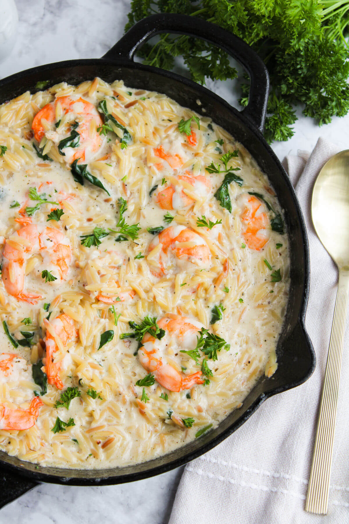 Lemon garlic shrimp orzo in a skillet with a spoon.