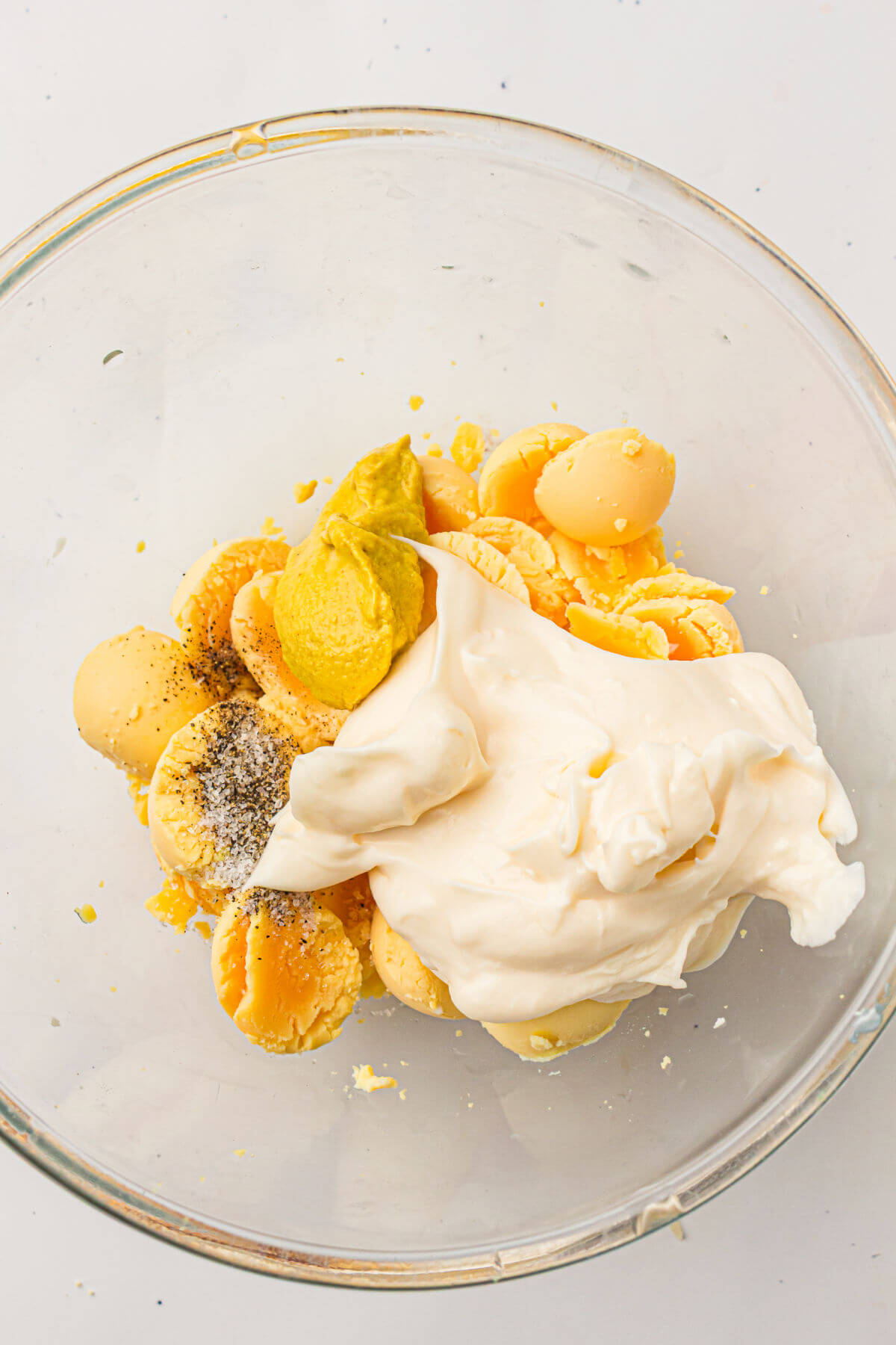 Egg yolks and ingredients  for easy deviled eggs recipe in a glass mixing bowl.
