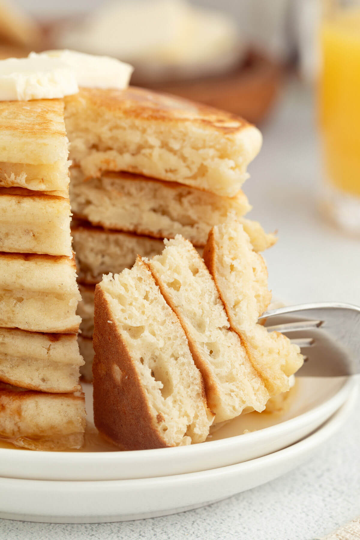 Fluffy sourdough pancakes in a tall stack with butter and maple syrup.