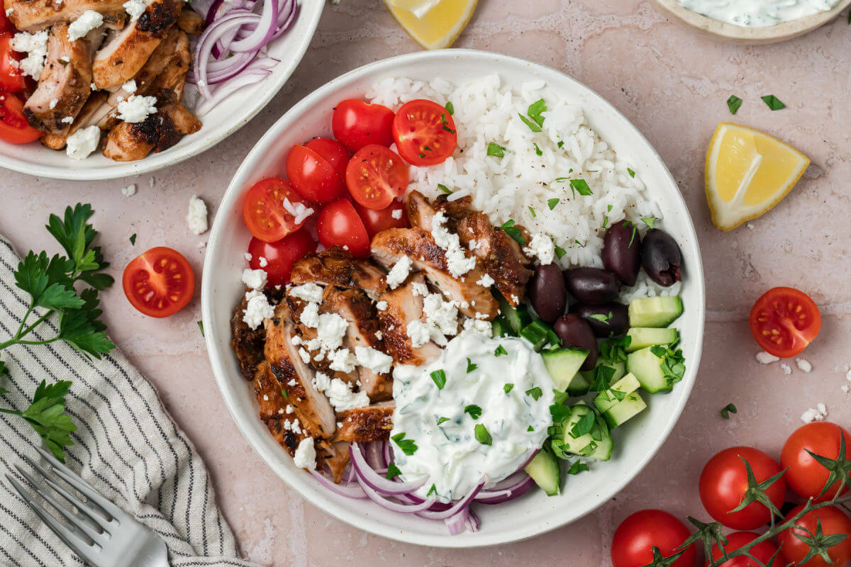Greek chicken bowls with tzatziki sauce in serving bowls.