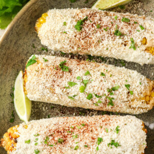 Easy Mexican street corn recipe with lime wedges on a serving platter.