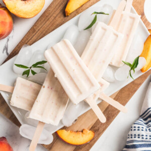 Peaches and cream popsicles on a cutting board with ice.