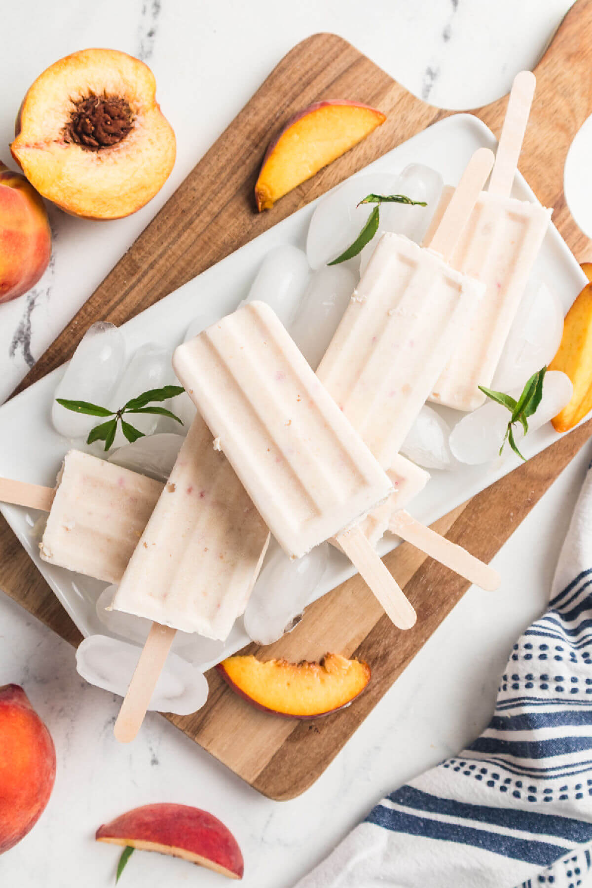 Peaches and cream popsicles on a cutting board with ice.