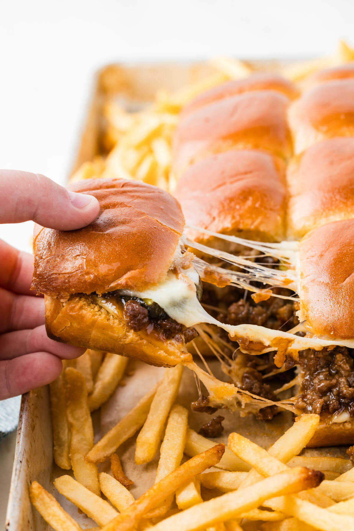 Sloppy joe sliders being pulled from the pan after baking.