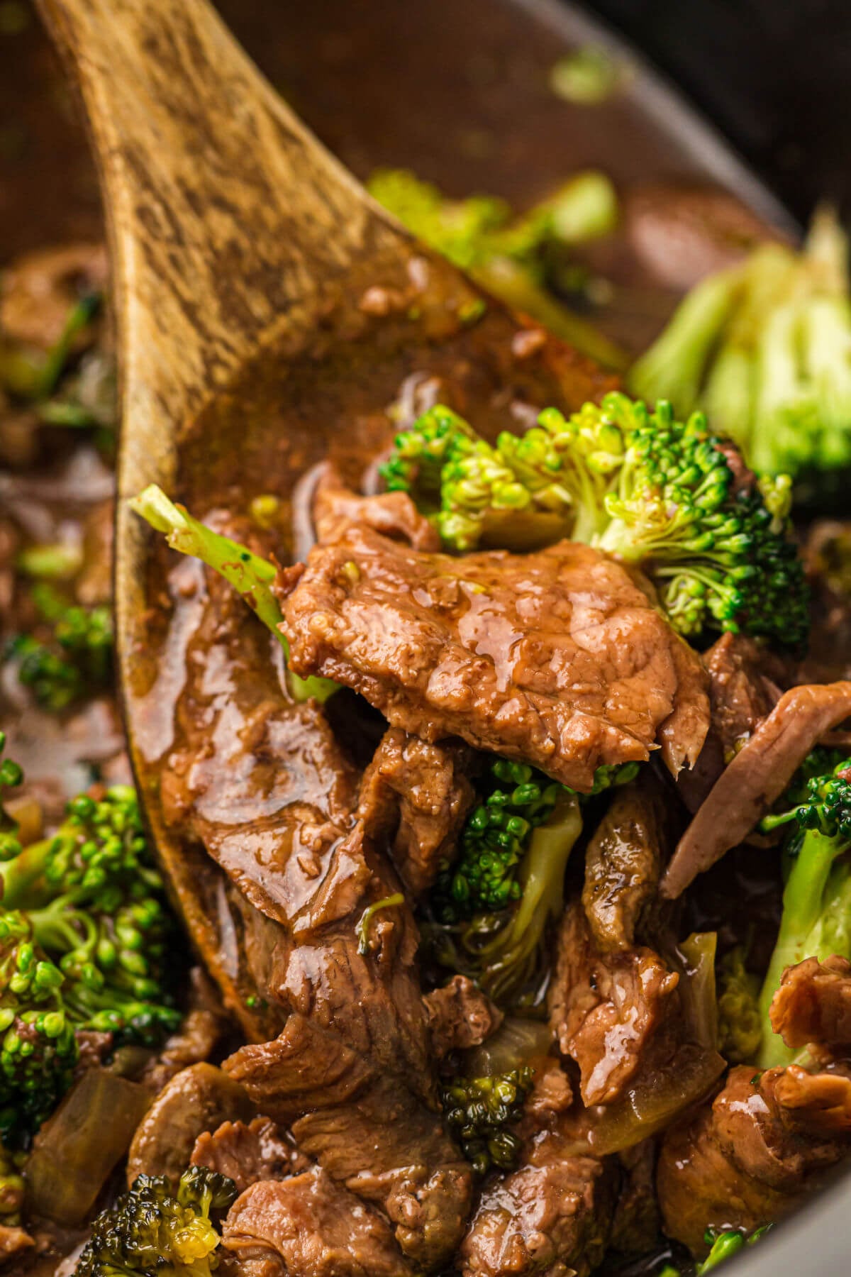 Slow cooker beef and broccoli on a wooden spoon.