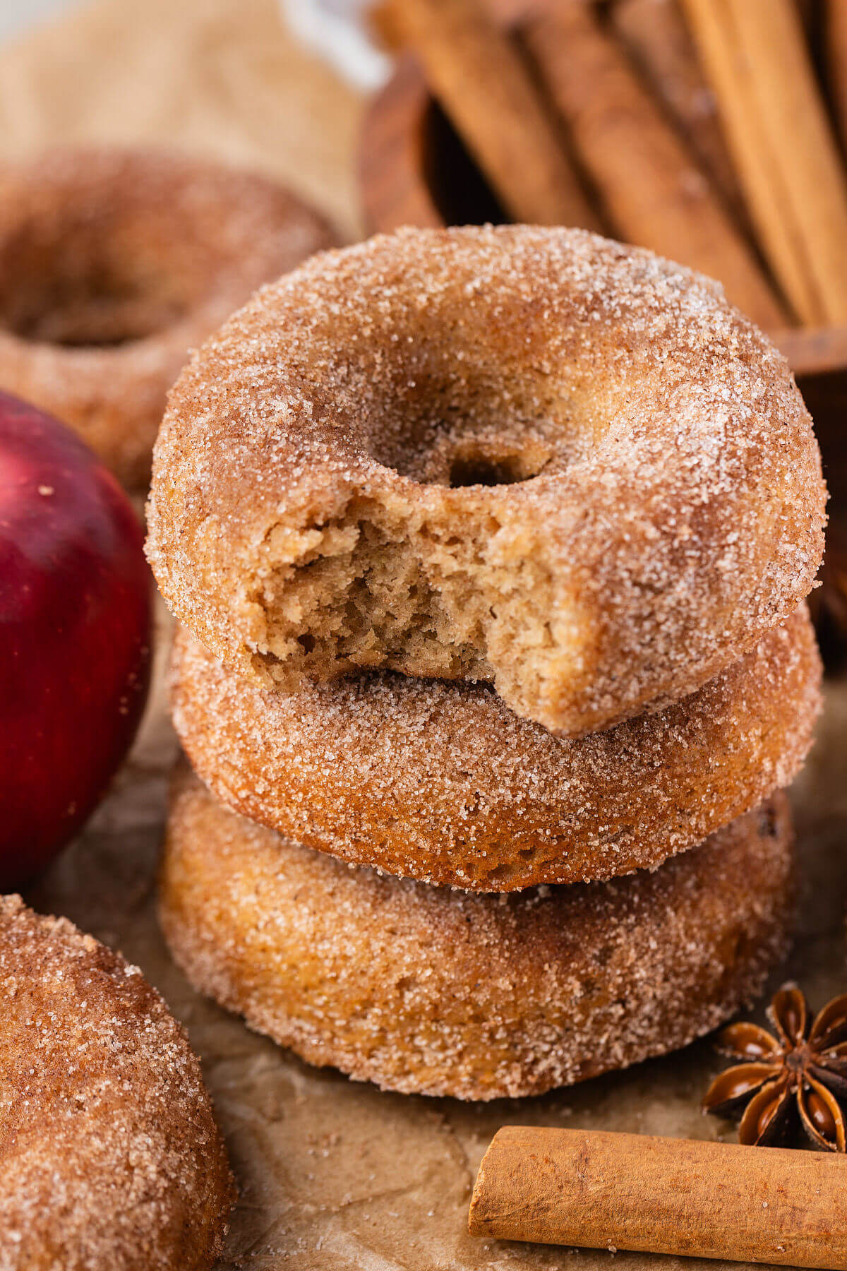 A stack of three sourdough apple cider donuts with a bite taken out of the top donut.