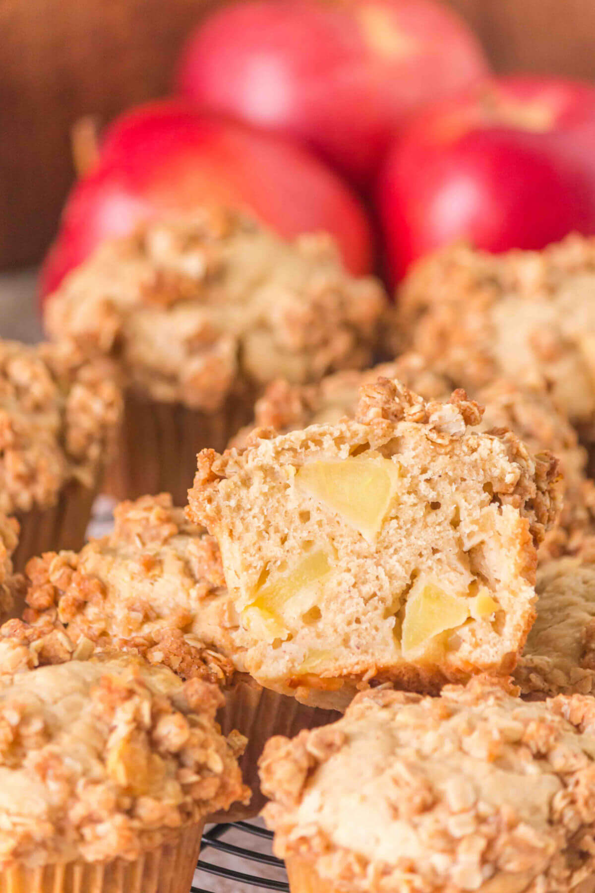 A pile of sourdough apple muffins with one muffin cut in half to see the inside.