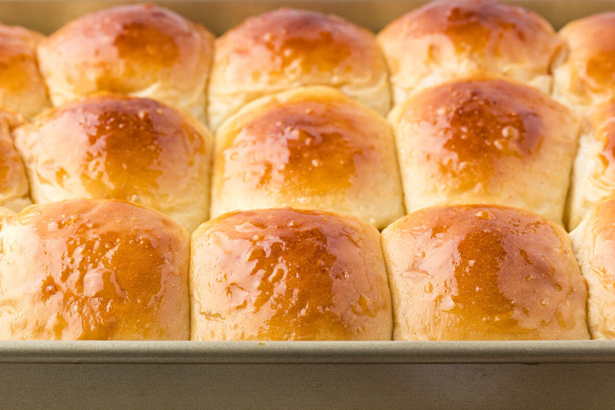 Pan of sourdough discard Hawaiian rolls with golden tops after baking.