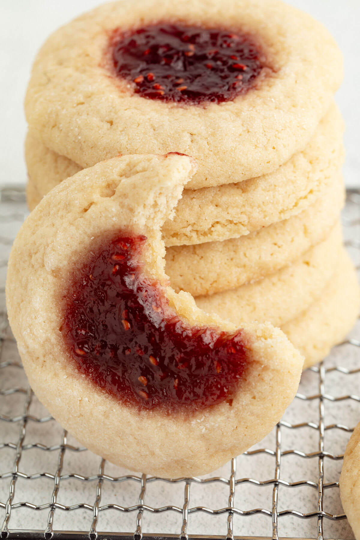 Sourdough thumbprint cookies in a stack, with a bite taken out of one.