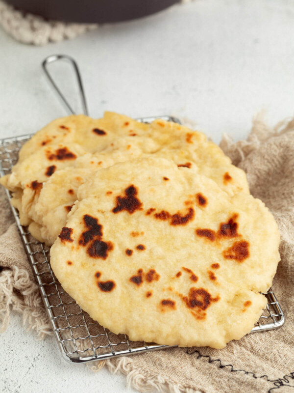 Sourdough naan in a stack on a wire cooling rack.